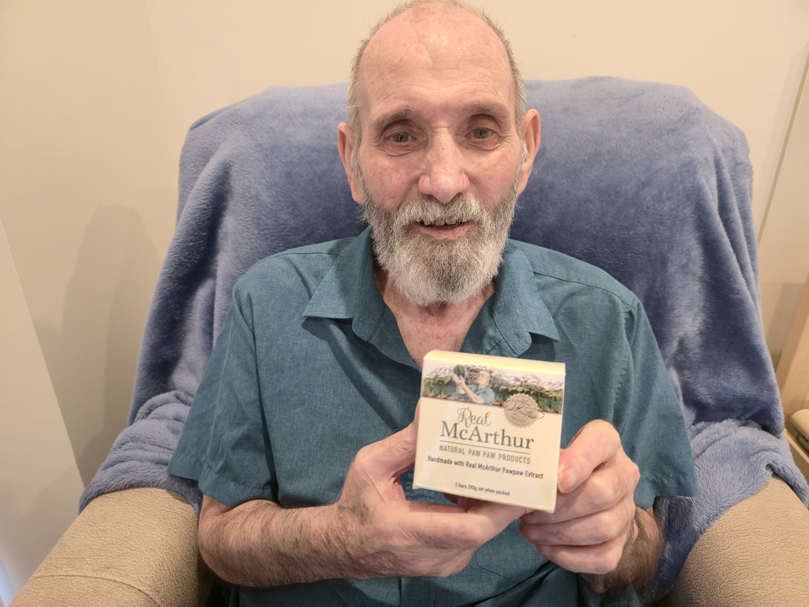 Tom McArthur, known as the Paw Paw Man, smiling and holding a box of Real McArthur natural paw paw soap